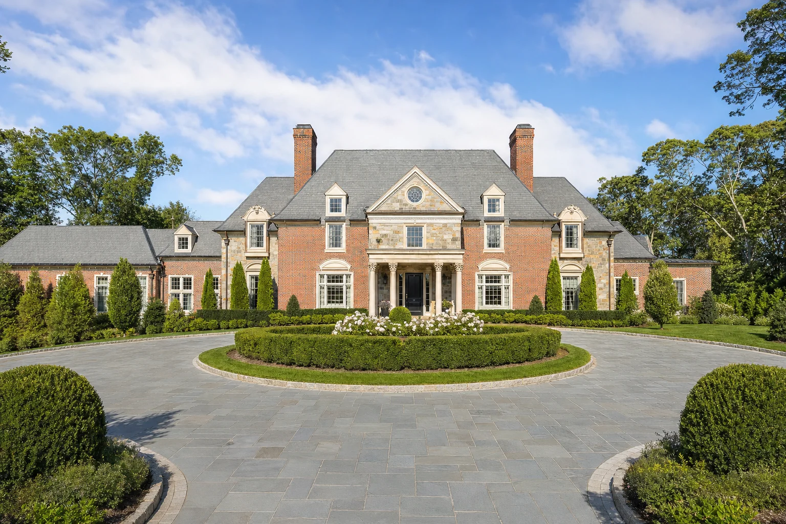 Symmetrical brick and stone Gold Coast Long Island estate with formal gardens in bright daylight